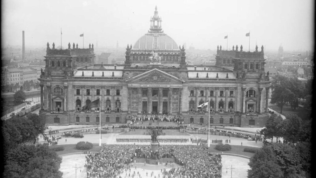 Blick auf das flaggengeschmückte Reichstagsgebäude von der Siegessäule aus gesehen, mit der Menschenmenge und der davorstehenden Ehrenkompanie, während der Verfassungsfeier am 11. August 1926. (© Bundesarchiv/Georg Pahl)