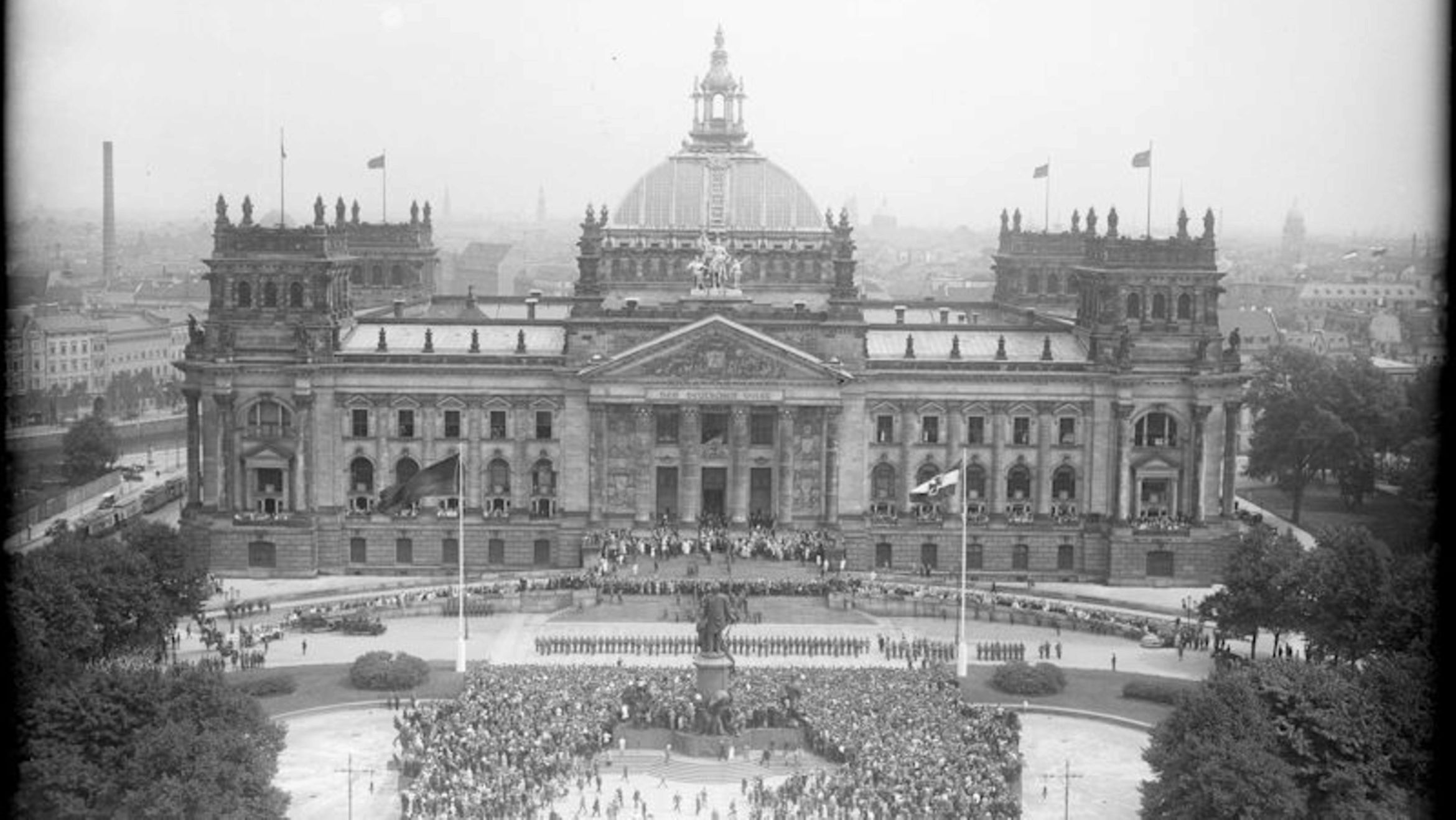 Blick auf das flaggengeschmückte Reichstagsgebäude von der Siegessäule aus gesehen, mit der Menschenmenge und der davorstehenden Ehrenkompanie, während der Verfassungsfeier am 11. August 1926. (© Bundesarchiv/Georg Pahl)